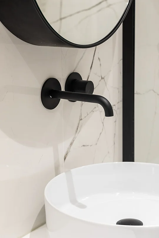 Robinet noir sur vasque blanc posé sur une crédence en marbre