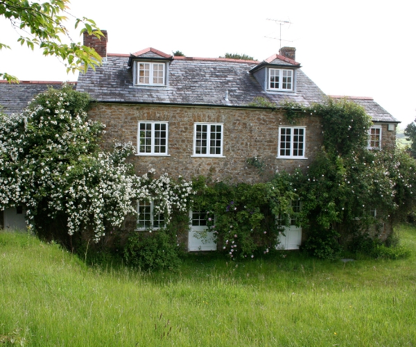 Résidence secondaire en France - Jolie maison de campagne en pierre avec toit en tuiles couverte des fleur grimpantes sur la façade