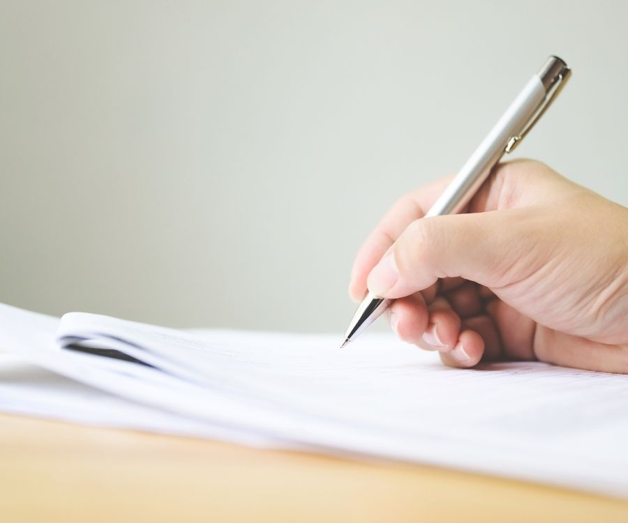 Demander l'assurance décennale avant de signer un contrat avec un architecte d'intérieur - Photographie montrant une main qui signe un papier